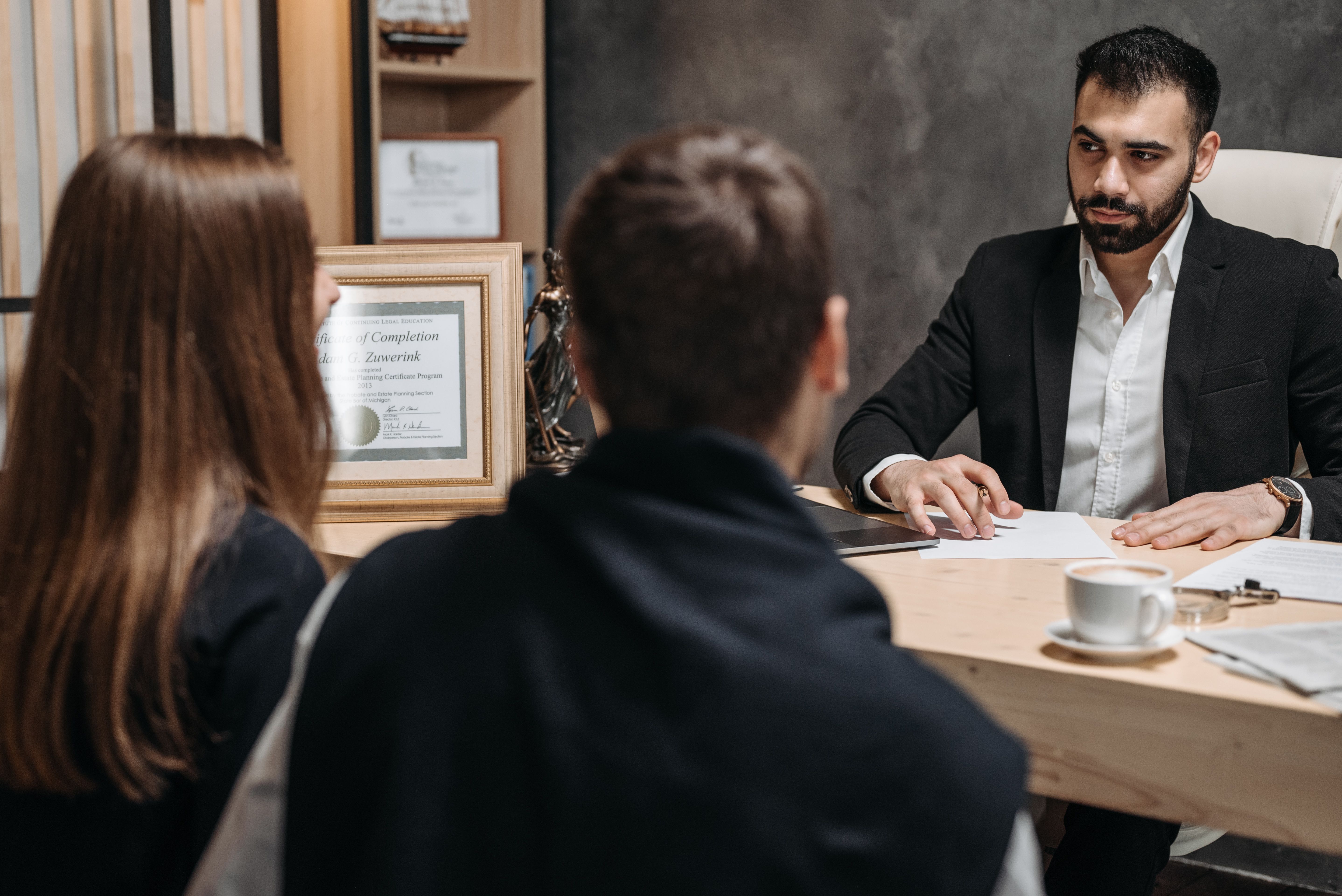 A professional reviewing documents with clients during a private, attentive office consultation.